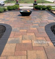 an outdoor patio with brick pavers and flower beds on either side, surrounded by landscaping