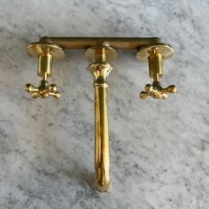 two golden handles on a marble counter top with gold fixtures and knobs in the middle