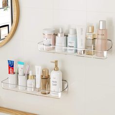 two glass shelves holding personal care products in front of a white tiled wall with a round mirror