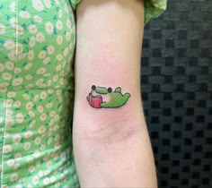 a woman's arm with a small tattoo of a crocodile and a book on it