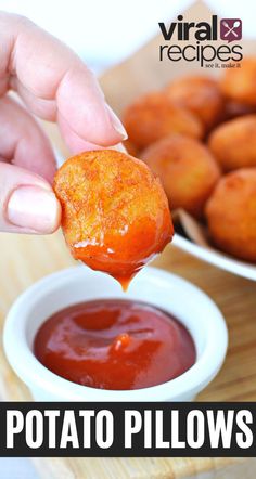 a person dipping some food into a bowl with ketchup on the side and another plate in the background