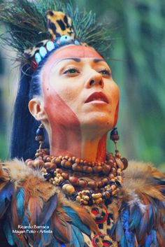 a woman with blue hair and feathers on her head is looking up at something in the air