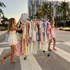 two women pushing a rack with clothes on it