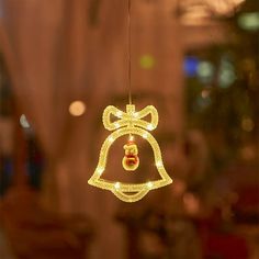 a lighted bell hanging from the ceiling in front of a window with lights on it