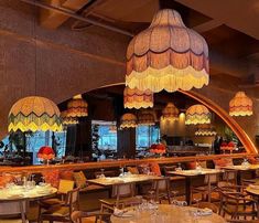 a restaurant with many tables and chairs, lights hanging from the ceiling over it's dining area