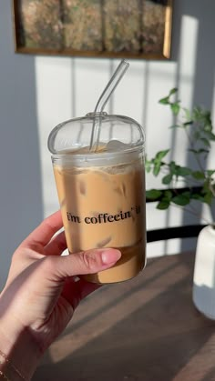 a person holding up a drink with a straw in it's cup and the words i'm coffee written on it