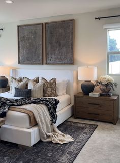 a large bed sitting next to two lamps on top of a dresser in a bedroom