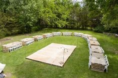 a large wooden dance floor in the middle of a grassy area with lots of tables and chairs around it