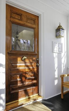 the sun is shining through the window onto an entryway with a wooden door and bench