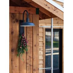 a light hanging from the side of a wooden building with a wreath on it's wall