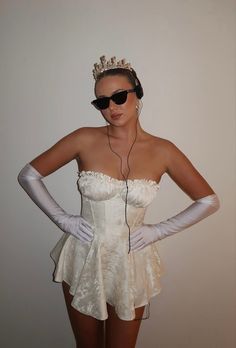 a woman wearing white gloves and a tiara is listening to music on her headphones