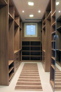 an empty walk in closet with lots of wooden shelves and shelving unit doors open