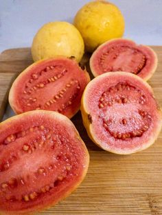 four pieces of watermelon sitting on top of a cutting board next to two lemons