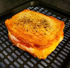 a grilled cheese sandwich sitting on top of a black grill grate covered in seasoning