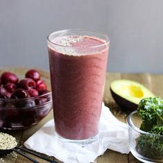 a smoothie in a glass next to other fruits and vegetables