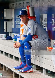 a baseball player sitting on the bleachers in front of some bottles and cups