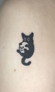 a black cat with a skull on it's back tattooing its eyes and tail