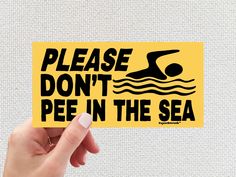 someone holding up a yellow sticker that says, please don't pee in the sea