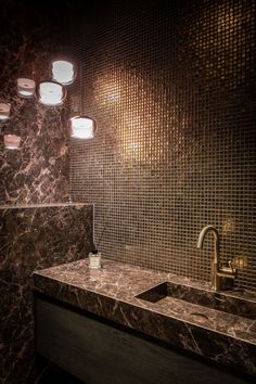 a bathroom with marble counter tops and lights on the wall above it's sinks