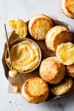 some biscuits and butter on a plate with a bowl of dipping sauce next to it