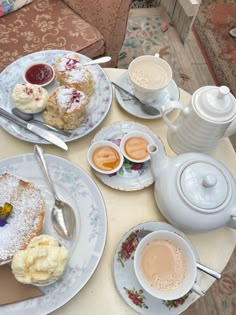 a table topped with plates and cups filled with desserts next to teapots