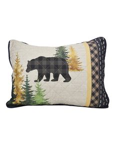 a black bear pillow with trees and plaid border on it's side, sitting in front of a white background