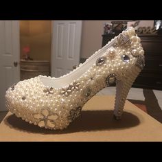 a pair of white high heels with pearls on them