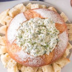 a white plate topped with a bagel covered in cream cheese and spinach dip