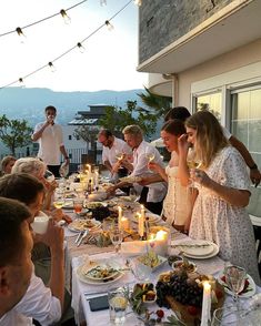 a group of people standing around a table with food and drinks in front of them