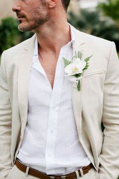 a man in a white shirt and jacket with a boutonniere on his lapel