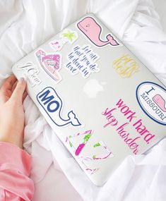 a person holding a laptop with many stickers on it's cover and the words work hard, happy holidays