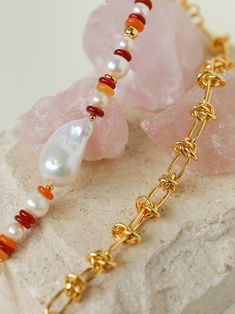 two bracelets with different colored beads and chains on top of a white stone slab