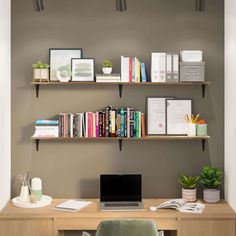 a laptop computer sitting on top of a wooden desk next to a book shelf filled with books