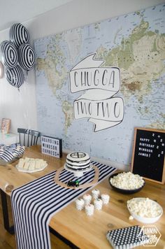 a table topped with lots of food next to a world map on a wall behind it