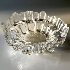 a clear glass bowl sitting on top of a white table next to a silver object