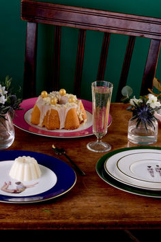 a table topped with plates and cake next to flowers on top of a wooden table