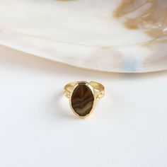 Adorn your finger with Brown Agate Ring. Handcrafted from copper and plated with 24k gold, it embodies timeless beauty. Embrace elegance with this unique, artisanal accessory that adds a touch of sophistication to your ensemble. Details: Materials: Copper, 24K Gold Plated, Agate Size: adjustable from 6 to 8 ring sizes. Nickel Free Important info: Please note that our collection is meticulously curated by a diverse array of makers and designers within friends. Be aware that for certain items, we Gold Open Ring With Natural Stones, Gold Brass Crystal Ring With Gemstone, Gold Crystal Ring With Natural Stones, Elegant Gold Crystal Ring With Cabochon, Spiritual Gold Rings With Natural Stones, Elegant Brown Rings With Natural Stones, Gold Oval Crystal Ring With Natural Stones, Oval Gold Crystal Ring With Natural Stones, Gold Rings With Natural Stones For Gift