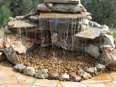 an outdoor fountain with rocks and water running down it