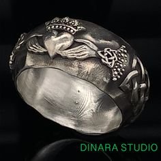 a silver ring with an image of a frog on it's side and the words dinara studio