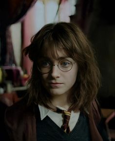 a young harry potter with glasses and a tie in a room full of other items