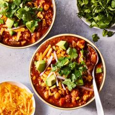 three bowls filled with chili, cheese and tortilla chips on top of a table