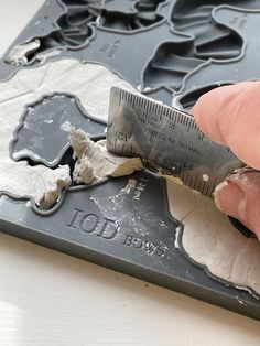 a person holding a ruler in front of a piece of paper that has been torn off