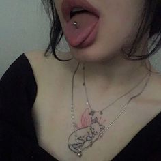 a woman sticking her tongue out with a tattoo on her chest