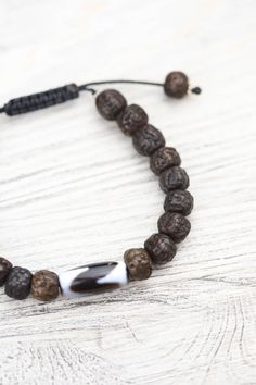 A DharmaShop exclusive design, this wrist mala is handmade in Nepal from vintage style dark rudraksha beads with a true agate Tiger Tooth Dzi bead centerpiece. Dzi beads are believed to bring protection and prosperity to the wearer. Each bead is unique, making your bracelet one-of-a-kind. The rudraksha beads are sanded in a tumbler for comfort before being naturally stained and oiled to achieve their beautiful dark color and aged appearance. Rudraksha beads are known for their healing properties Spiritual Hand Knotted Bracelets With Round Beads, Adjustable Brown Mala For Healing, Adjustable Agate Hand-strung Mala, Spiritual Adjustable Hand-knotted Beaded Bracelets, Spiritual Hand-knotted Adjustable Beaded Bracelets, Adjustable Hand-strung Agate Mala, Adjustable Hand Knotted Spiritual Beaded Bracelets, Adjustable Hand-knotted Spiritual Beaded Bracelets, Traditional Brown Beaded Bracelets With Natural Stones