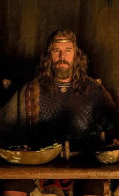 a man with long hair wearing armor and holding a bowl