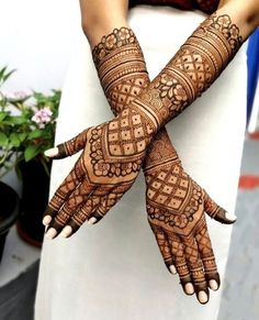 two hands with henna tattoos on them and one hand holding the other's arm