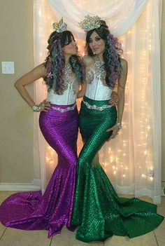 two women dressed in mermaid costumes standing next to each other with their hands on their hipss