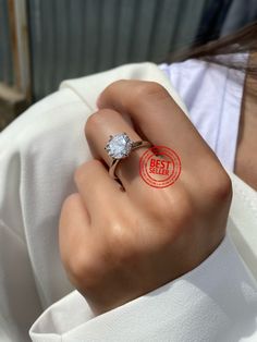 a woman wearing a ring with a diamond on it's finger and the stamp below her