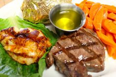 a white plate topped with meat and veggies next to foil wrapped in foil