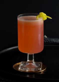 a close up of a drink in a glass on a table with a black background